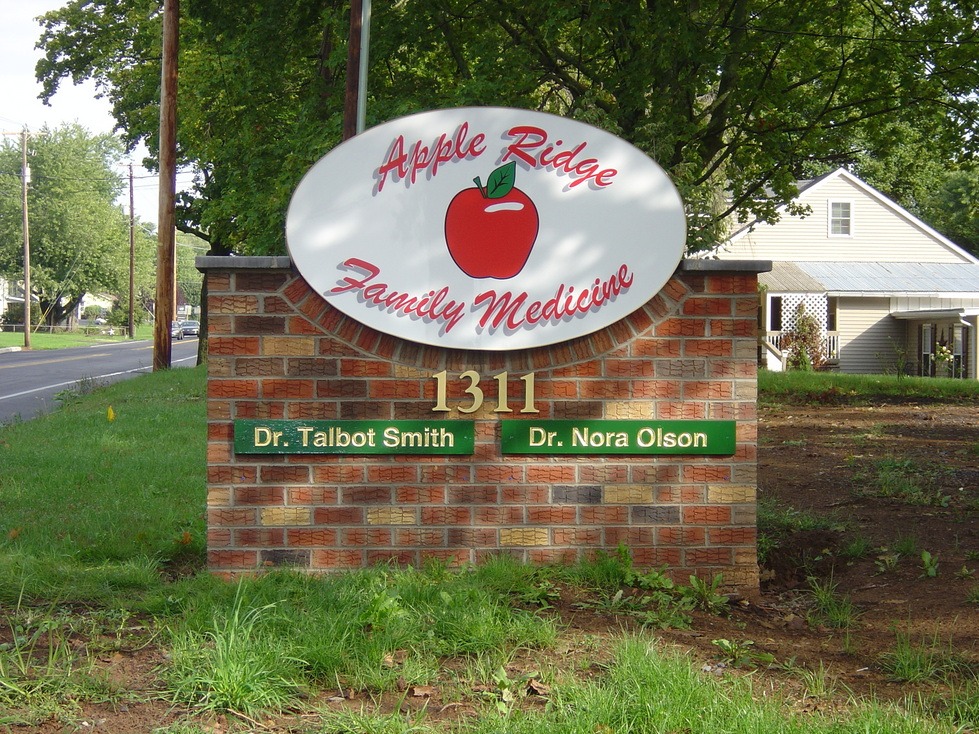 A brick sign for Apple Ridge Family Medicine at 1311, listing Dr. Talbot Smith and Dr. Nora Olson.