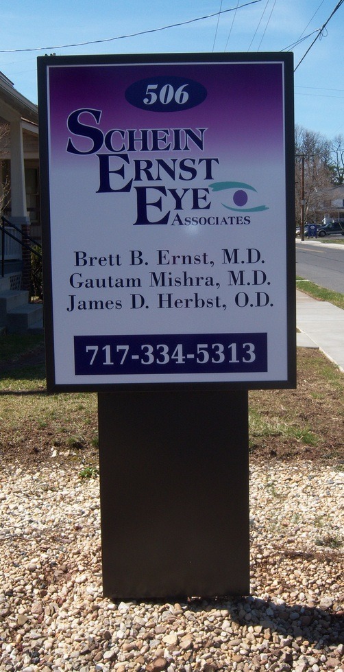 Sign for Schein Ernst Eye Associates listing doctorsโ names and phone number outside a medical office at 506.