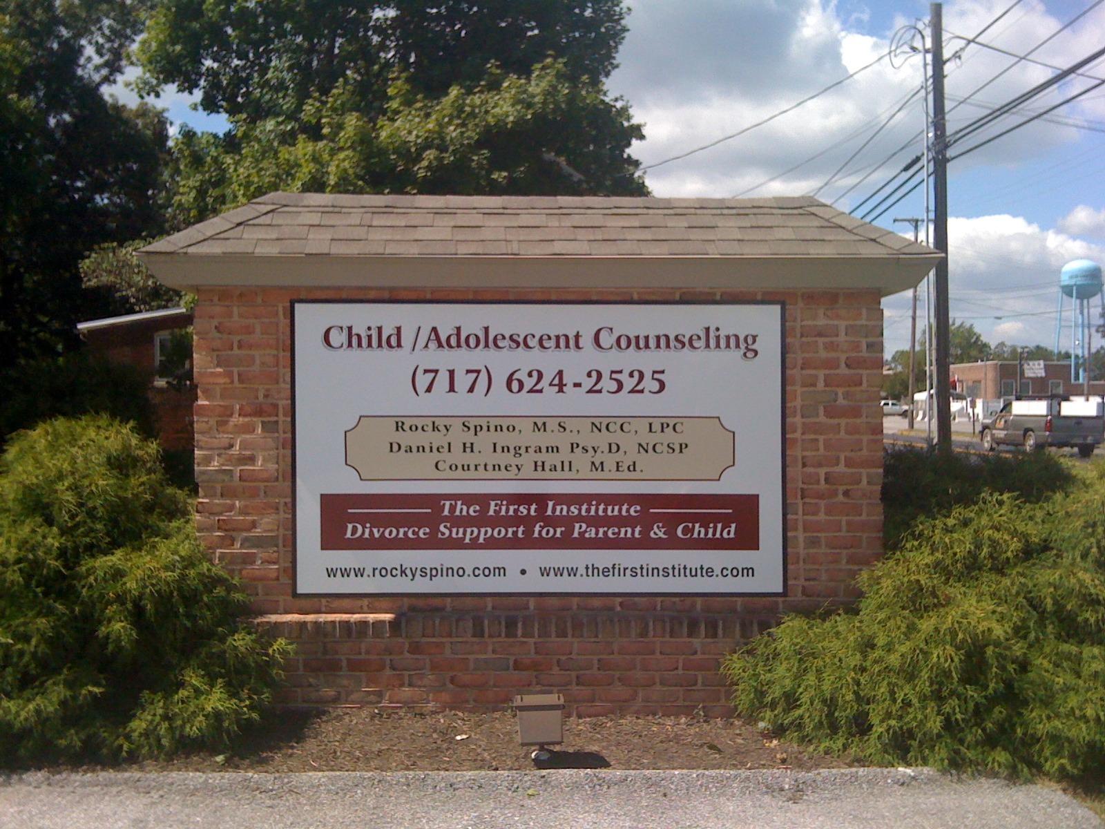 Sign for Child/Adolescent Counseling and Divorce Support services with contact info and counselor names in front of a brick wall.