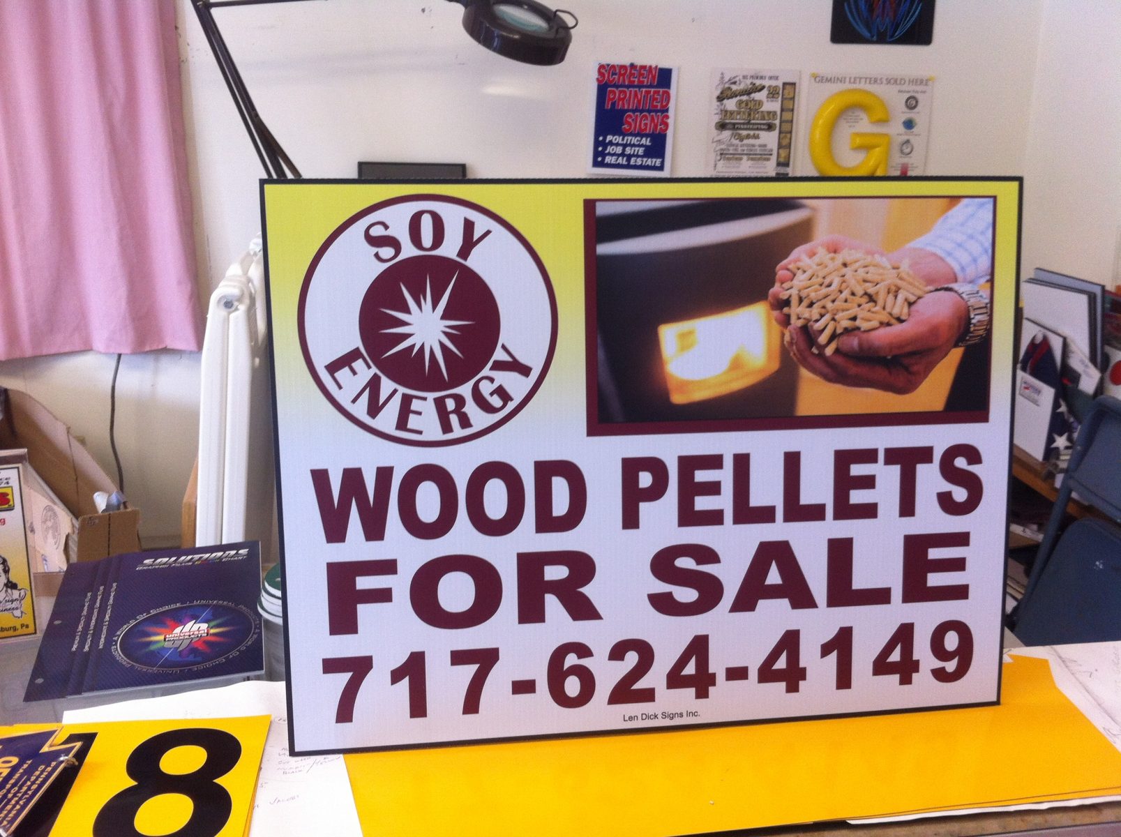 Sign advertising wood pellets for sale by Soy Energy, with contact number and an image of wood pellets in a hand.