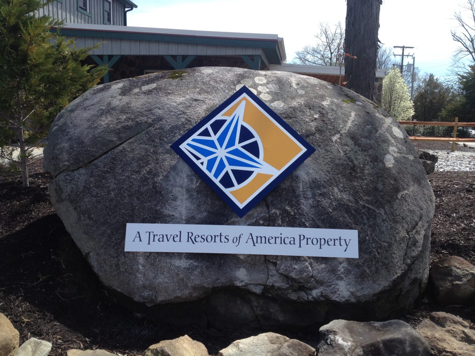 A large rock displays a Travel Resorts of America Property sign with a blue and yellow geometric logo.