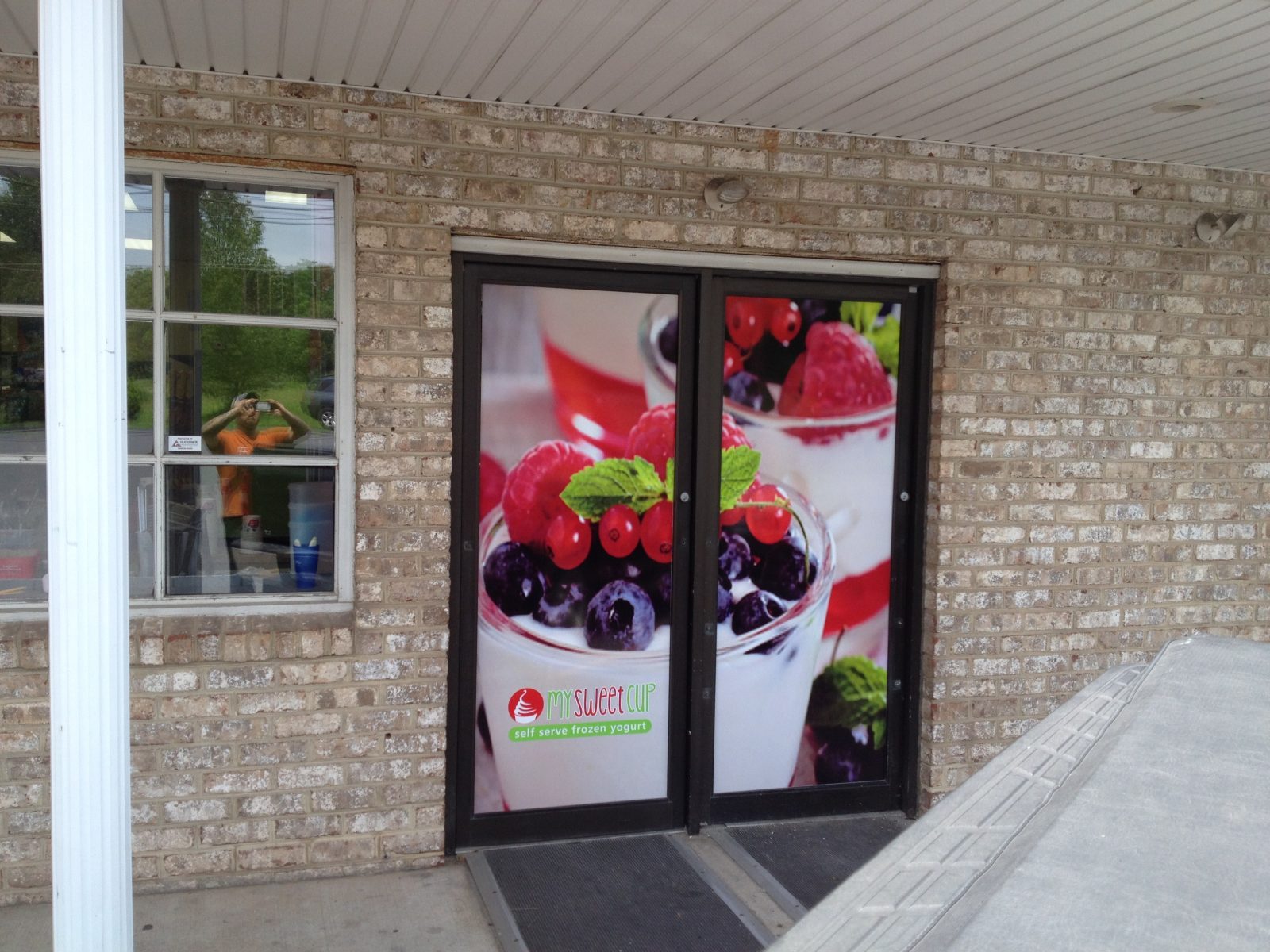 Glass doors with a large image of berry parfaits and a "My Sweet Cup" logo on a brick storefront.