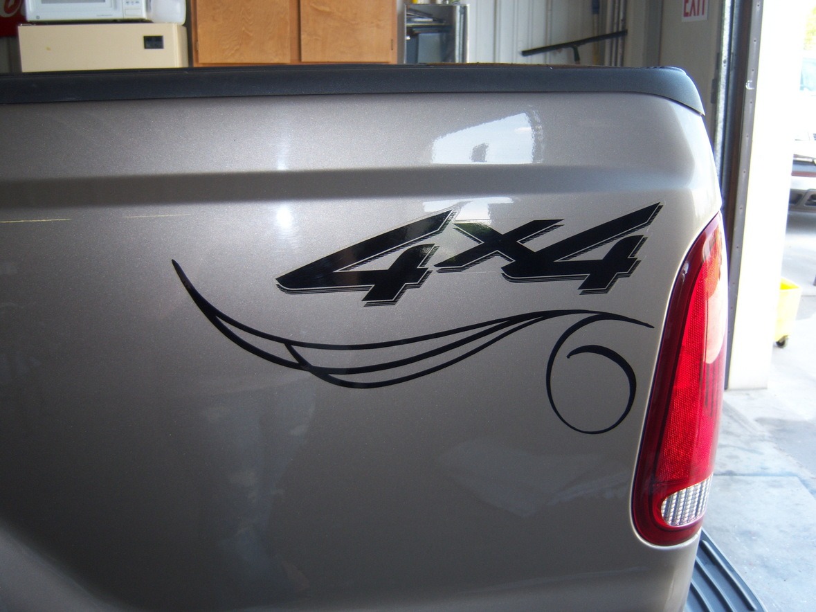 Close-up of a truck bed showing a "4x4" decal with a black swirl design near the rear taillight.