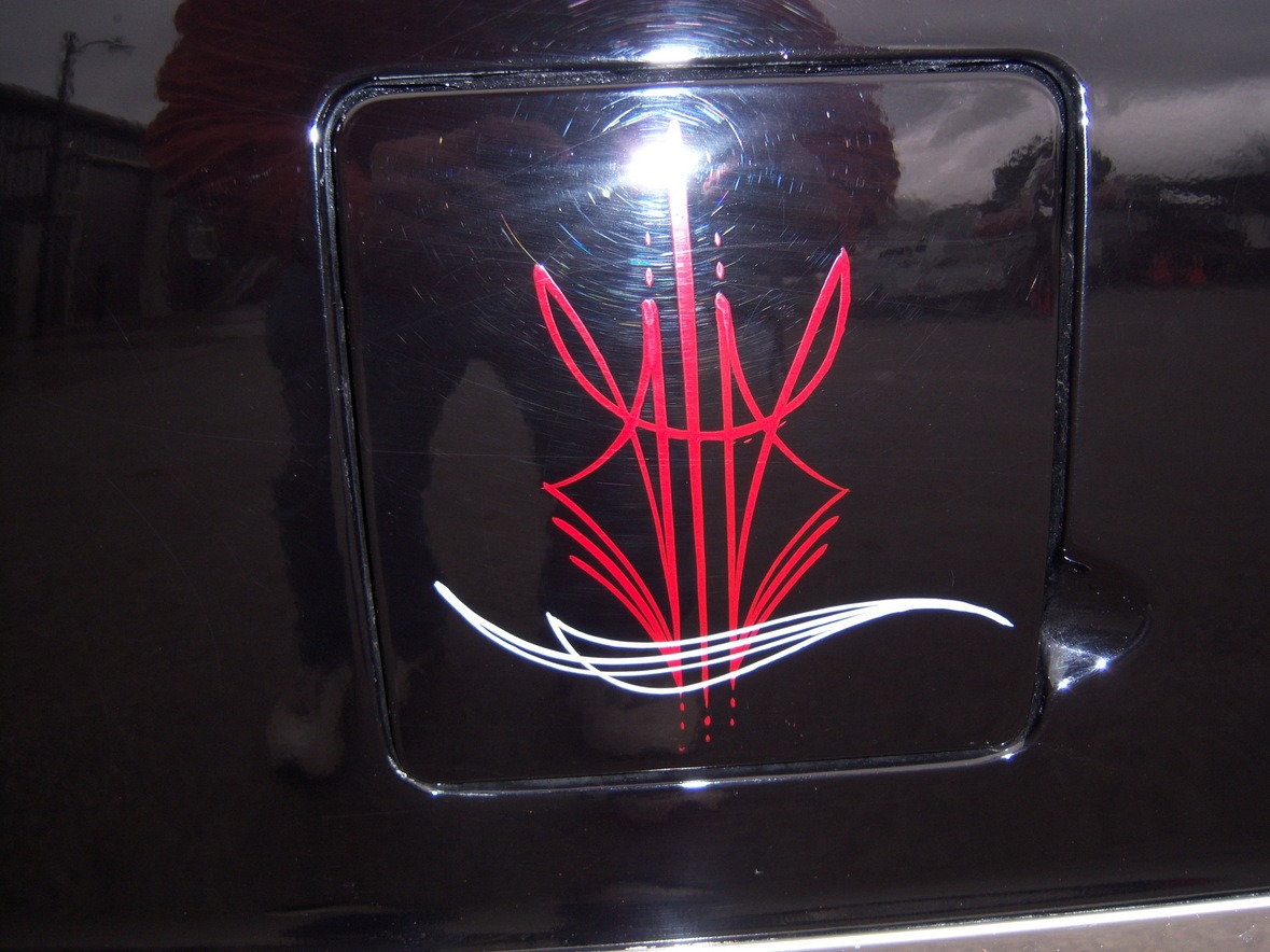 Red and white pinstripe design painted on a glossy black car surface with a faint reflection of a person visible.