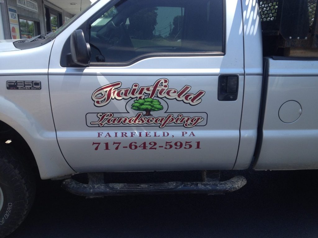 White truck door with "Fairfield Landscaping, Fairfield, PA, 717-642-5951" and a tree logo printed on the side.